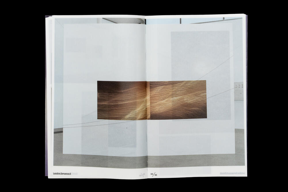 An open catalog spread displays a minimalist gallery interior with white walls and a wooden artwork mounted centrally, featuring abstract brown and golden tones.