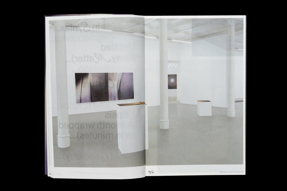 An interior view of a minimalist gallery space with white walls and columns. Framed photographic works are displayed on the left wall above white pedestals, with additional artwork visible in the adjacent room.